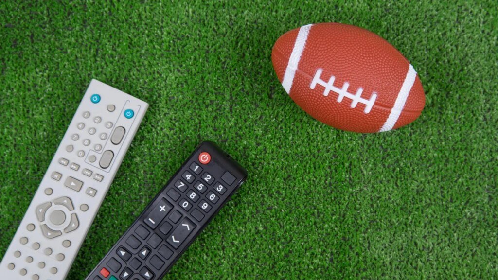 A football and remote controls on green turf
