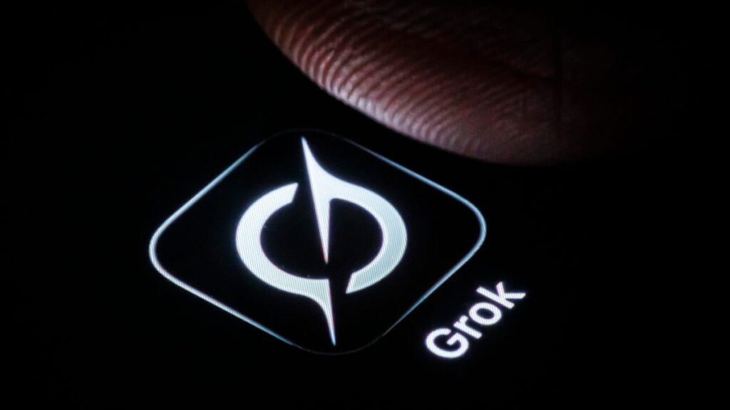 the Grok logo is shown on a dark phone background with the slightest bit of a thumb hovering over it