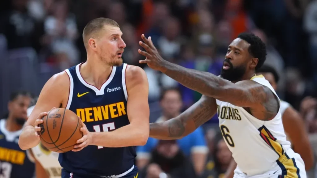 El serbio Nikola Jokić, de los Nuggets de Denver, trata de avanzar frente a DeAndre Jordan, de los Pelicans de Nueva Orleáns, el sábado 24 de octubre de 2026